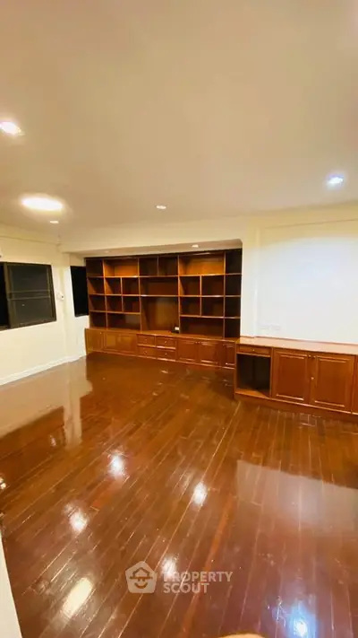 Spacious living room with polished wooden floors and built-in shelving