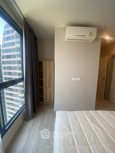 Modern bedroom with large window and air conditioning in high-rise building
