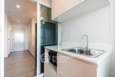 Modern kitchen with sleek cabinetry and built-in microwave in a bright apartment.
