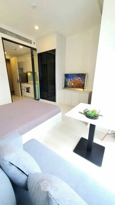 Modern studio apartment with open layout, featuring a cozy living area and compact kitchen.