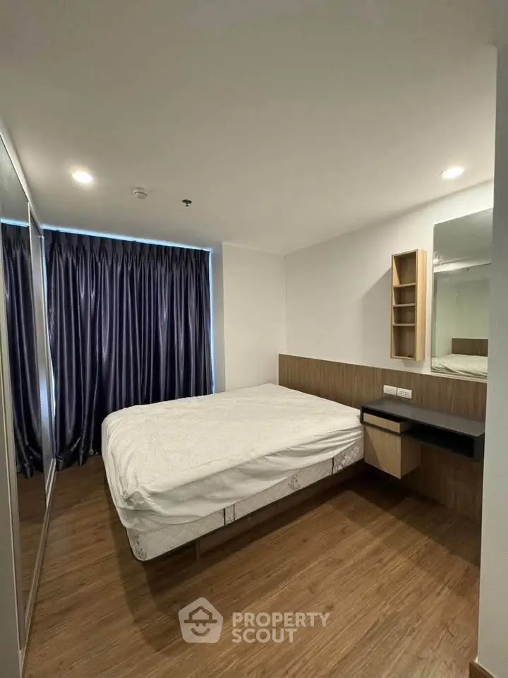 Modern bedroom with wooden flooring and large mirrored wardrobe