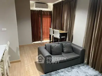 Modern living room with cozy sofa and dining area, featuring elegant curtains and wooden flooring.