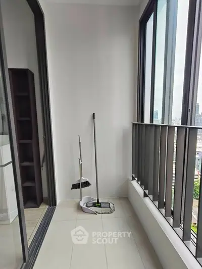 Modern balcony with city view, featuring sleek railings and cleaning tools, perfect for urban living.