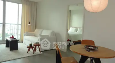 Modern living room with cozy seating and dining area, featuring a view into a stylish bedroom.