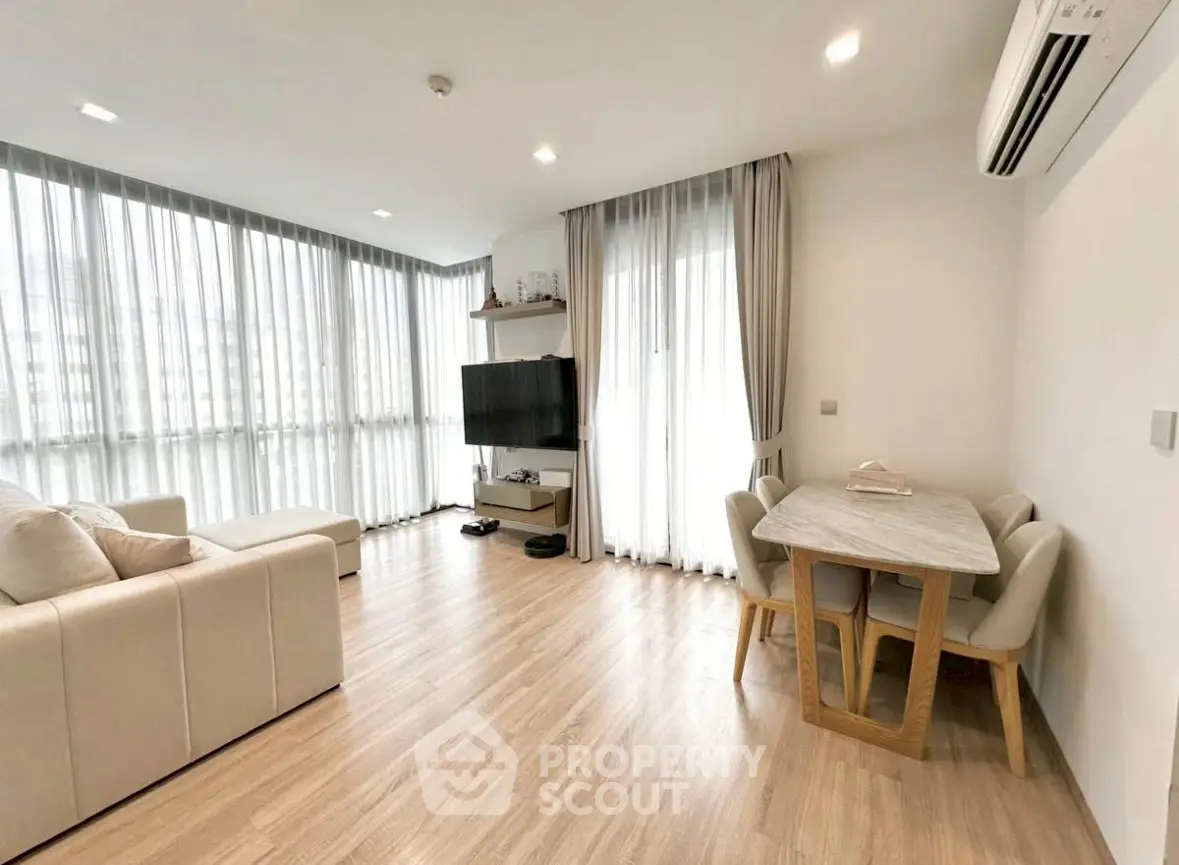 Spacious modern living room with large windows and elegant dining area