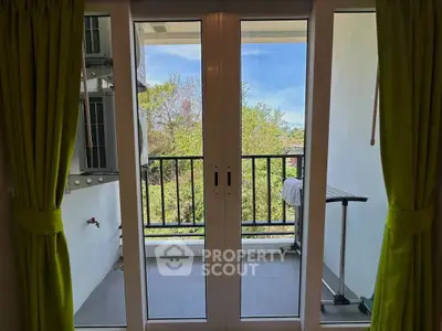 Charming balcony view with lush greenery and modern sliding doors.