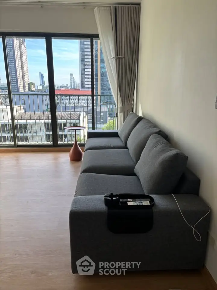 Modern living room with gray sofa and city view from balcony