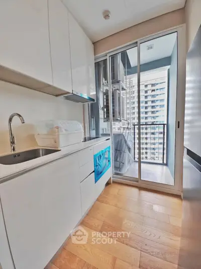 Modern kitchen with sleek cabinets and balcony view in high-rise apartment.