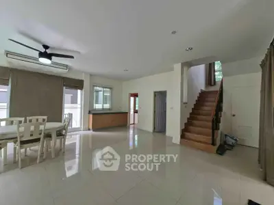 Spacious modern living room with dining area and staircase in a bright, open-plan layout.