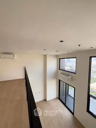 Modern duplex apartment with high ceilings and large windows offering city views.
