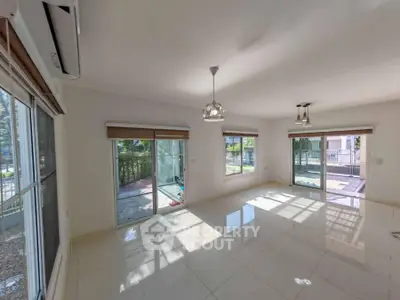 Spacious sunlit living room with large windows and garden view