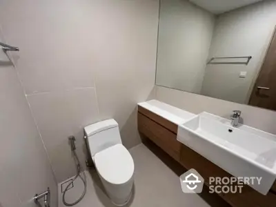 Sleek modern bathroom with a long vanity, large mirror, and a wall-mounted toilet, showcasing a minimalist and clean design.