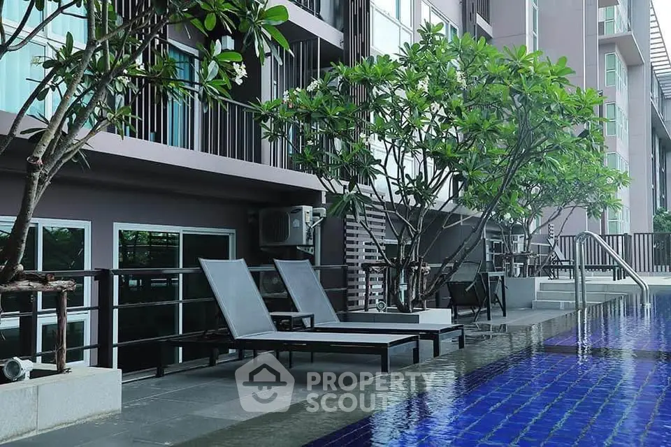 Luxurious poolside view with modern apartment backdrop and lush greenery.