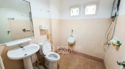 Spacious bathroom with modern fixtures and natural light, featuring a toilet, urinal, and shower area.