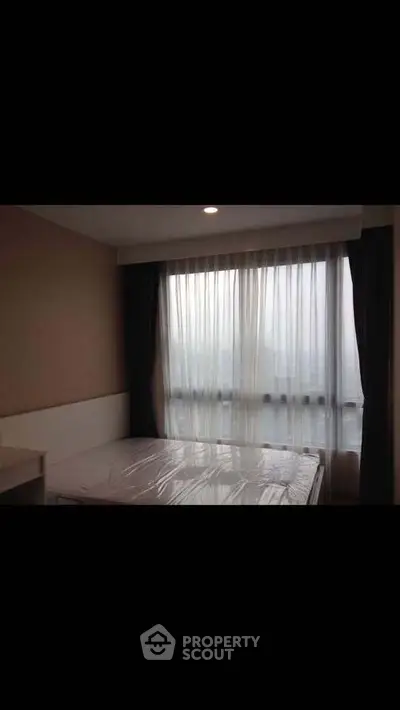 Cozy bedroom with large window and natural light, perfect for relaxation and comfort.