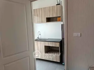 Modern compact kitchen with sleek wooden cabinets and minimalist design.