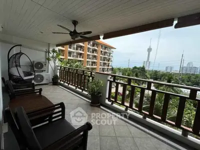 Spacious balcony with city view, modern seating, and ceiling fan in a high-rise apartment.