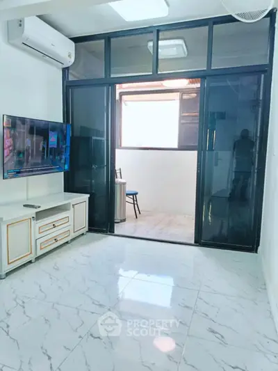 Modern living room with marble flooring and glass doors leading to balcony.
