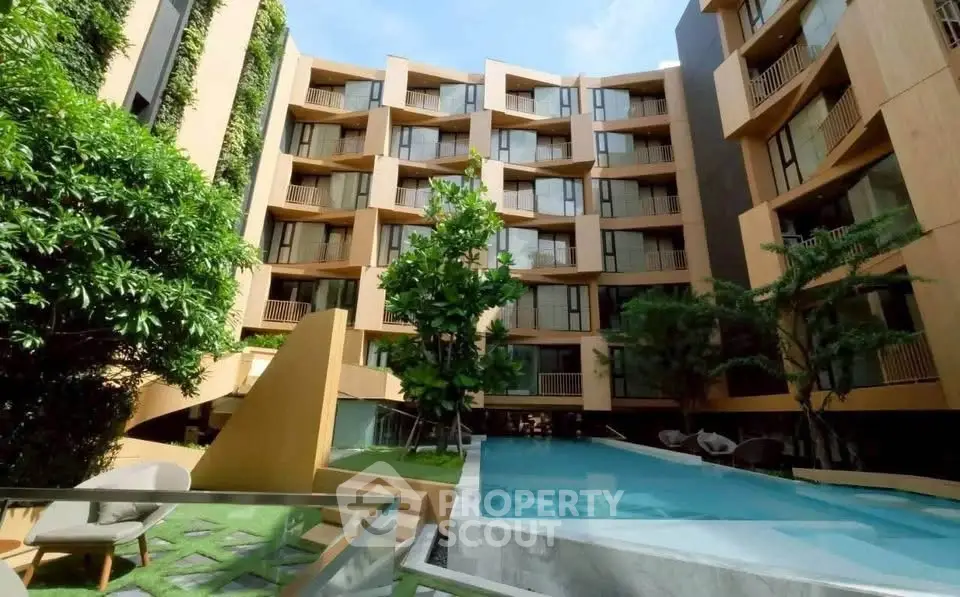 Modern apartment building with lush greenery and inviting pool area, perfect for urban living.