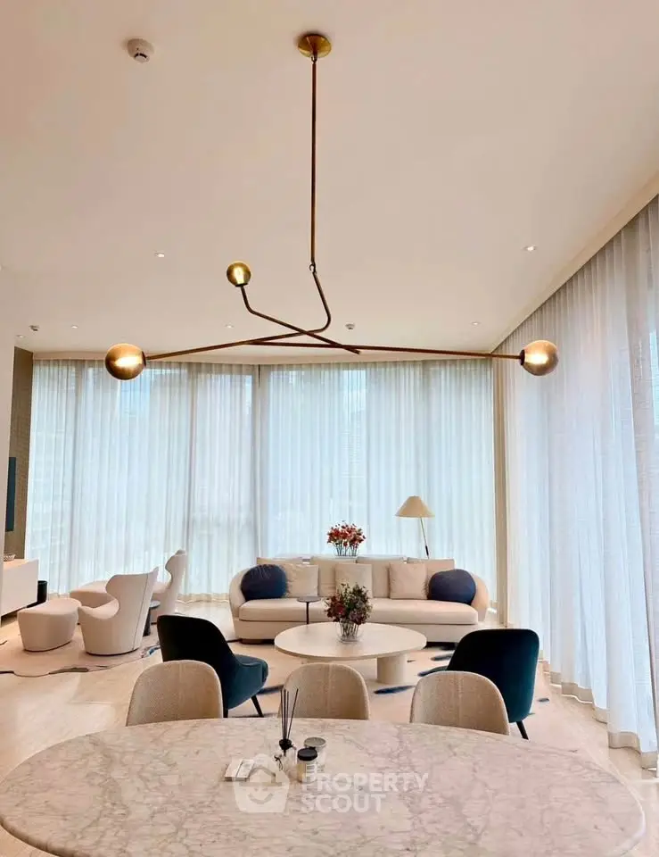 Luxurious modern living room with elegant lighting and stylish furniture, featuring floor-to-ceiling windows.