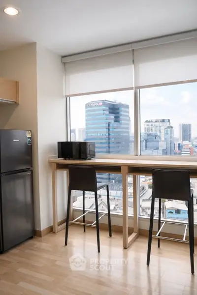 Modern kitchen with city view, featuring sleek bar stools and large windows for natural light.