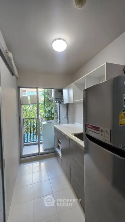 Modern kitchen with sleek appliances and balcony view in urban apartment