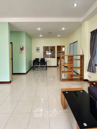 Spacious living room with modern furniture and elegant tile flooring in a well-lit apartment.