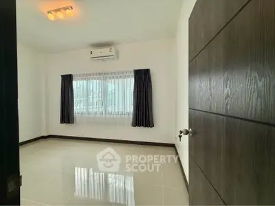 Spacious empty room with large window and air conditioning, perfect for customization.
