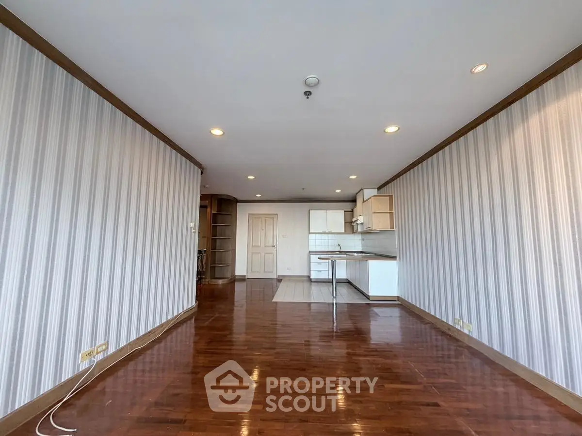 Spacious open-plan living room with wooden flooring and modern kitchen area.