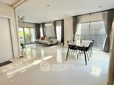 Spacious modern living room with dining area, large windows, and elegant decor.