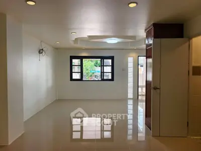 Spacious unfurnished living room with large window and glossy tiled floor