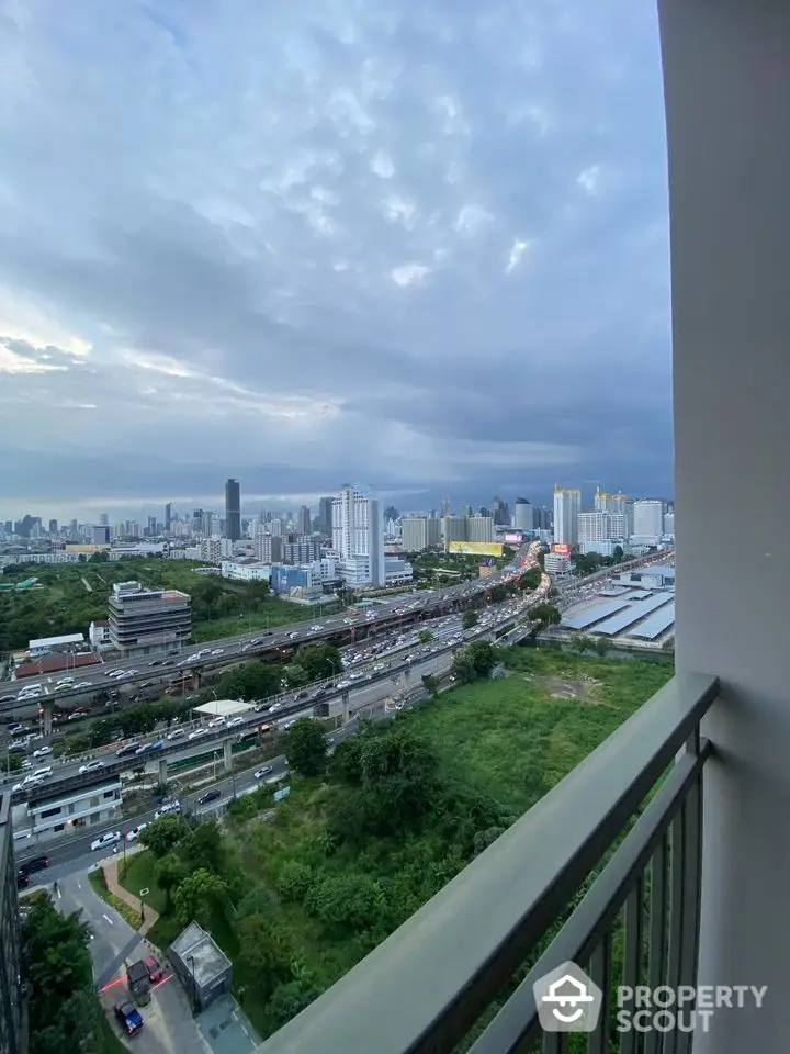 Stunning cityscape view from high-rise balcony overlooking urban skyline and lush greenery.