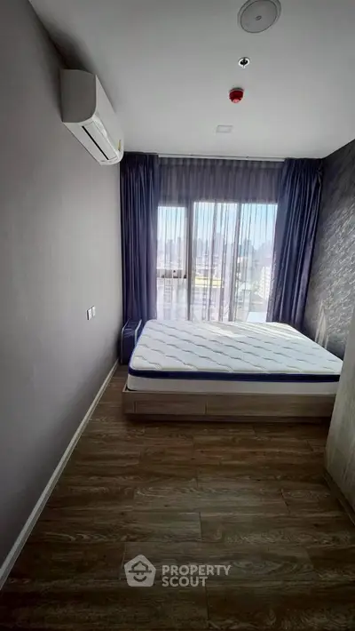 Modern bedroom with large window and city view, featuring sleek design and natural light.
