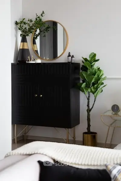 Stylish modern living room with chic black cabinet, round mirror, and lush green plant for elegant decor.