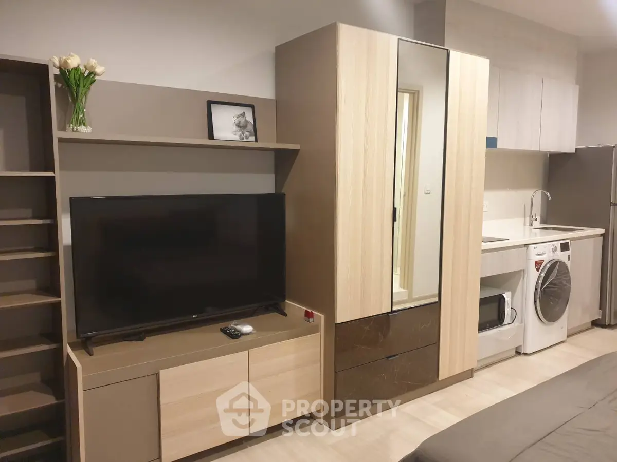 Modern studio apartment with sleek furniture and integrated kitchen appliances.