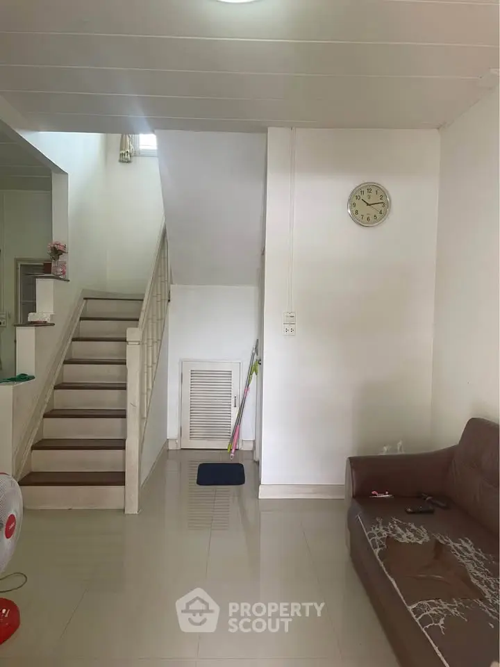 Spacious living area with modern staircase and cozy seating, ideal for family gatherings.