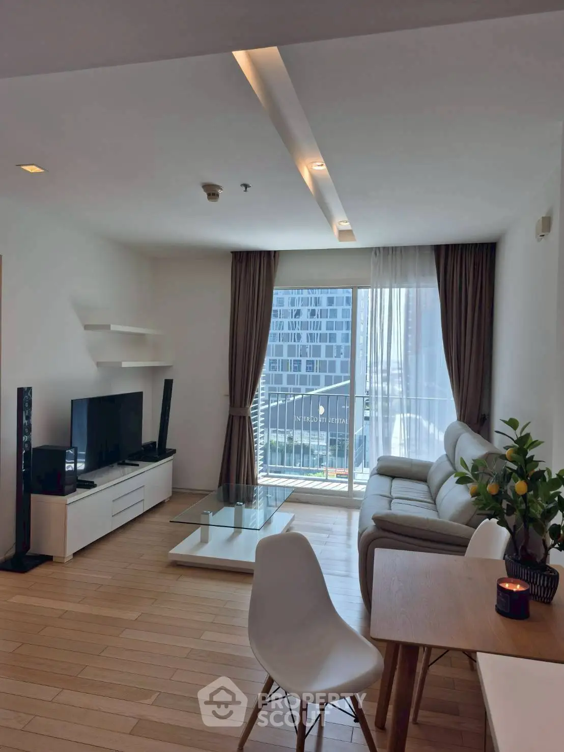 Modern living room with sleek furniture and city view balcony.
