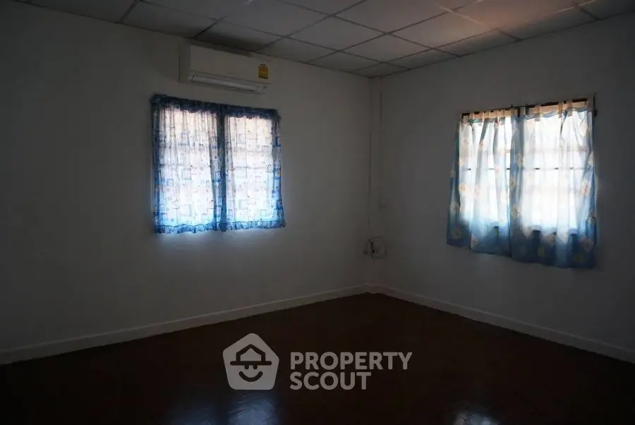 Spacious empty room with air conditioning and two curtained windows