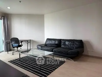 Modern living room with sleek black leather sofa and glass coffee table in a minimalist design.