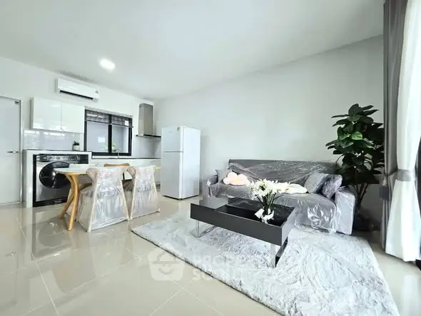 Modern open-plan living room with sleek kitchen, stylish furniture, and natural light.