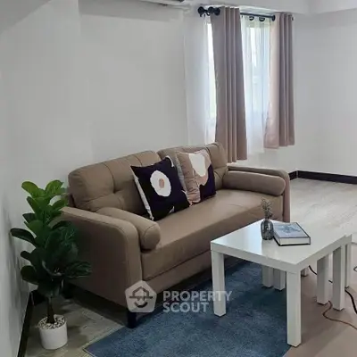 Cozy living room with beige sofa, white coffee table, and natural light from window.