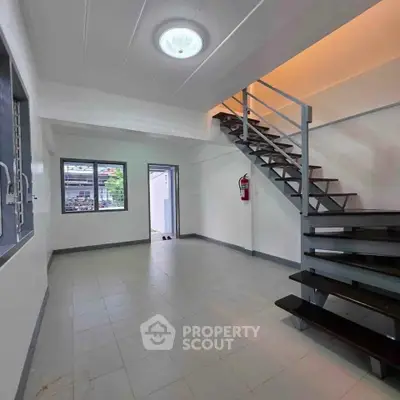 Modern interior with sleek staircase and large windows in a bright, open living space.