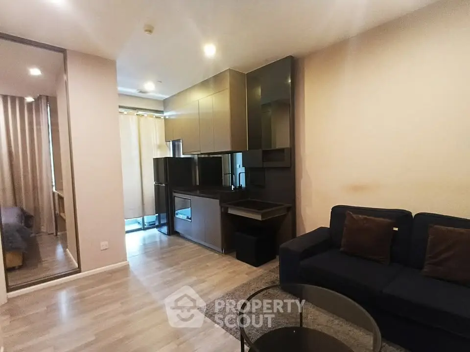 Modern living room with open kitchen and cozy seating area in stylish apartment.