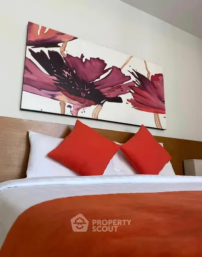 Modern bedroom with vibrant red accents and floral artwork above the bed.
