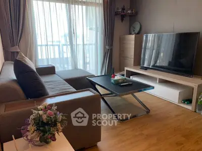 Modern living room with large TV, stylish sofa, and balcony view.