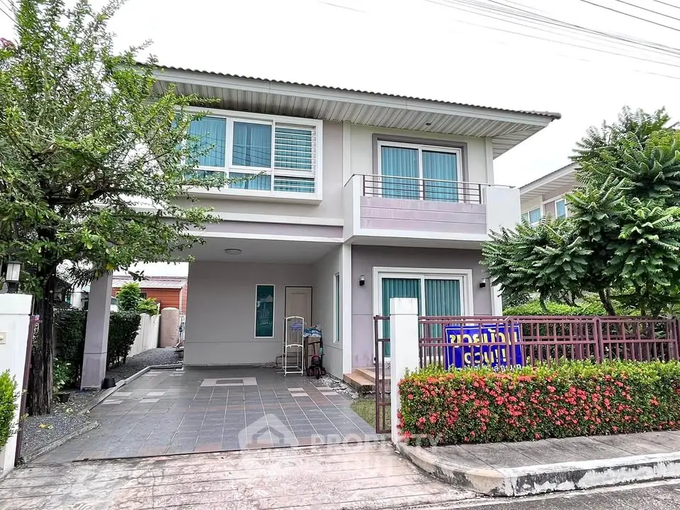 Modern two-story house with lush garden and spacious driveway in suburban neighborhood.