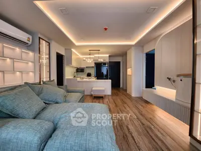 Luxurious modern living room with open kitchen, featuring elegant lighting and stylish decor.