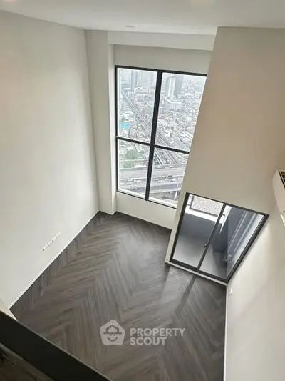 Spacious high-rise apartment with stunning city view and elegant herringbone flooring.