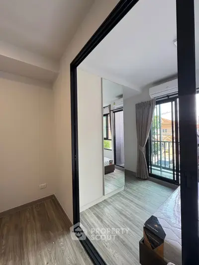 Modern bedroom with balcony access and wooden flooring in a stylish apartment.