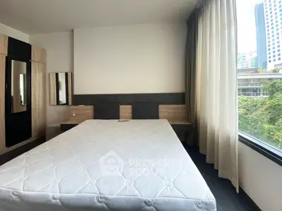 Spacious bedroom with large window offering city view, modern furnishings, and ample natural light.